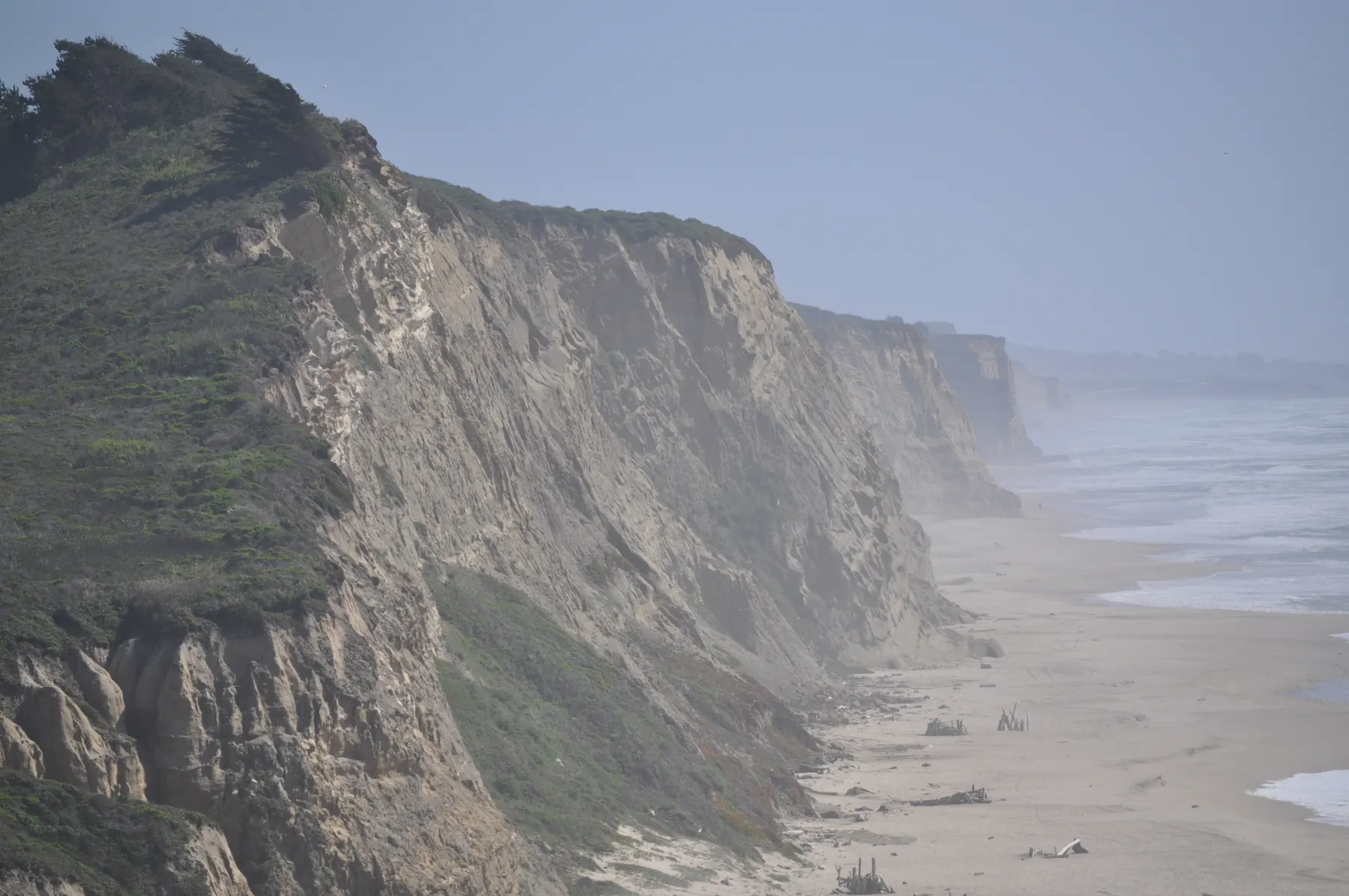 Tall coastal cliffs recede into mist above the Pacific near San Gregorio